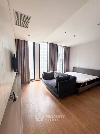 Modern bedroom with large windows and stylish furnishings in a high-rise apartment.