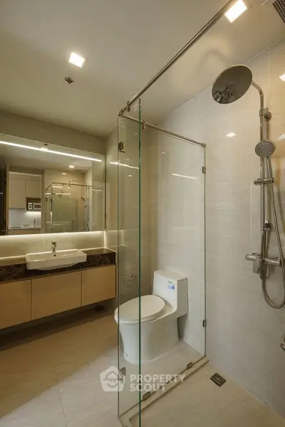Modern bathroom with glass shower enclosure and sleek fixtures in a contemporary apartment.