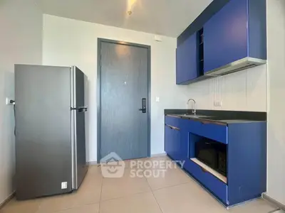Modern kitchen with blue cabinets and stainless steel fridge in sleek apartment