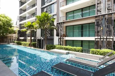 Modern apartment building with poolside view and lush greenery