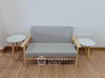 Modern minimalist living room with stylish sofa and side tables on wooden flooring.