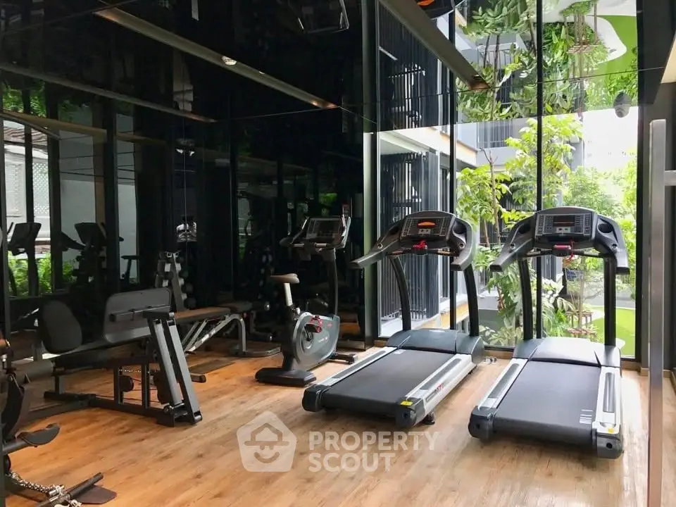 Modern gym with state-of-the-art equipment and lush garden views, perfect for fitness enthusiasts.
