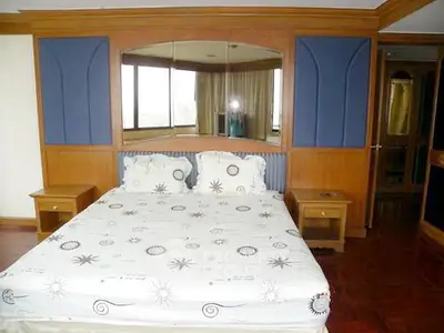 Spacious bedroom with elegant wooden paneling and large windows offering natural light.