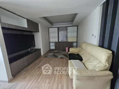 Spacious living room with modern wood flooring and cozy leather sofa, perfect for relaxation.
