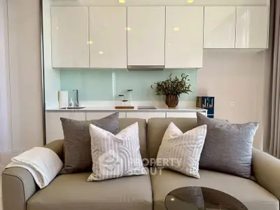 Modern living room with sleek kitchen, featuring stylish sofa and elegant cabinetry.