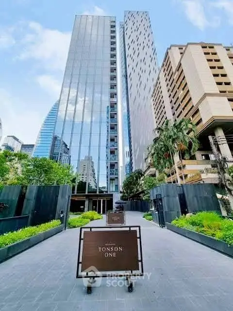 Luxurious high-rise building with modern architecture and lush greenery entrance.