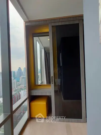 Modern high-rise apartment with stunning city view and cozy balcony area.