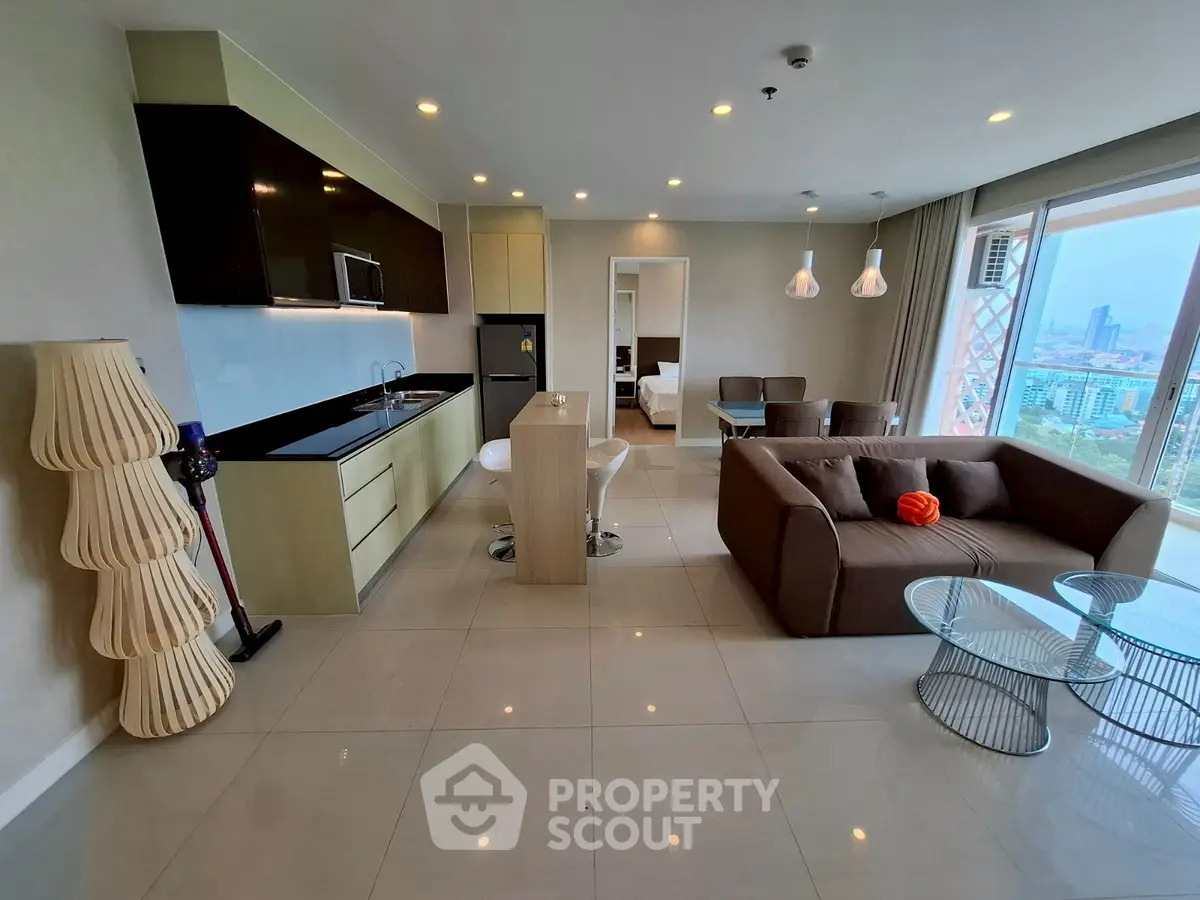 Modern open-plan living room with city view, sleek kitchen, and stylish furniture.