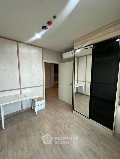 Modern bedroom with sleek mirrored wardrobe and minimalist desk setup.