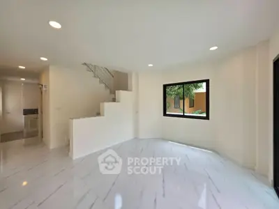 Spacious modern living room with elegant marble flooring and large window for natural light.