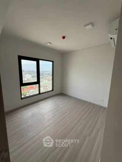 Spacious empty room with large window offering stunning city view, perfect for customization.
