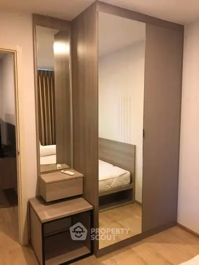 Modern bedroom with sleek wardrobe and mirror, showcasing minimalist design and ample storage space.