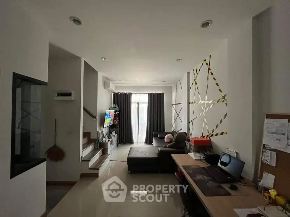 Modern living room with cozy sectional sofa and home office setup, featuring stylish decor and natural light.