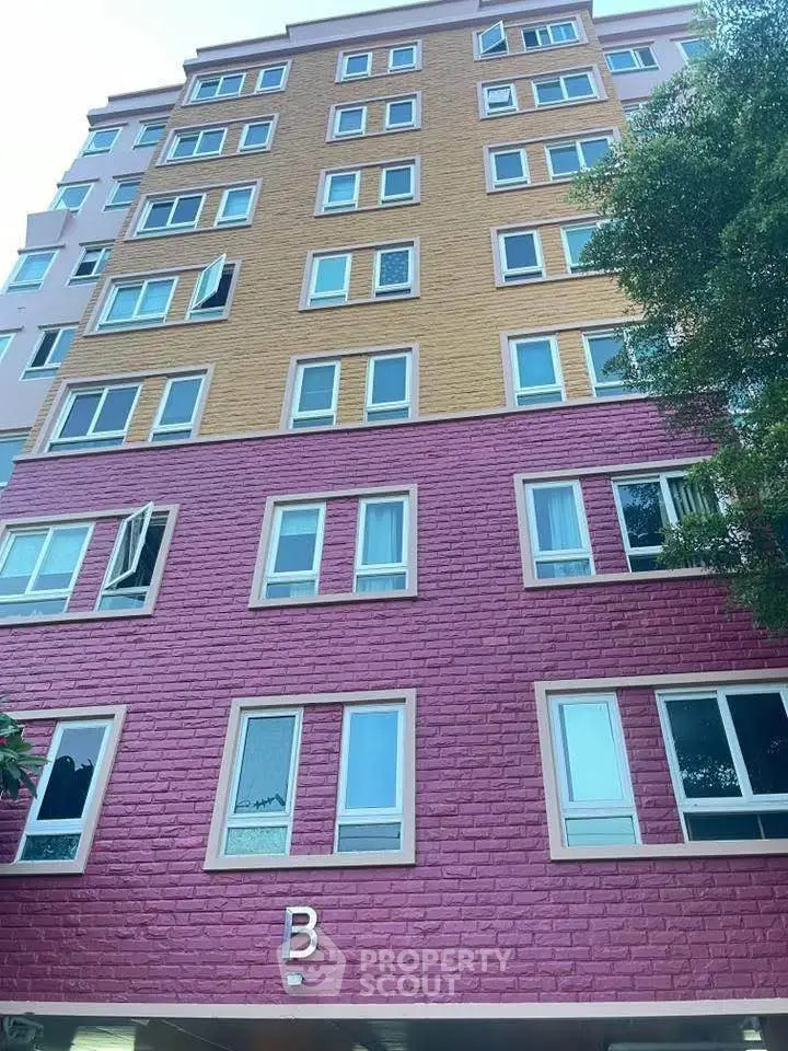 Colorful multi-story residential building exterior with vibrant pink and orange facade.