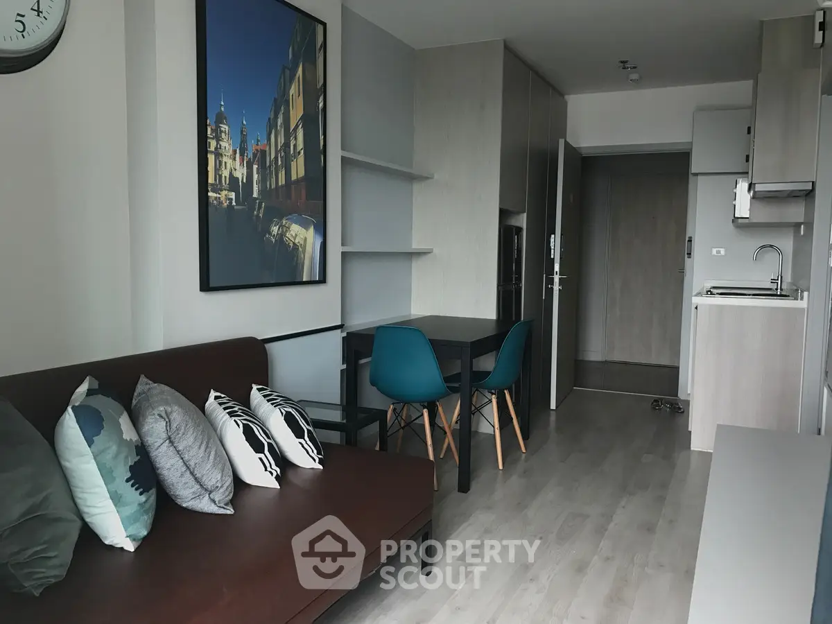 Modern living room with stylish decor and compact kitchen in open layout apartment.