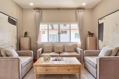 Elegant living room with cozy sofas, stylish decor, and natural light from large window.