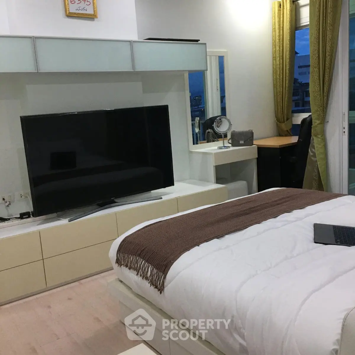 Modern bedroom with large TV and cozy decor, perfect for relaxation.