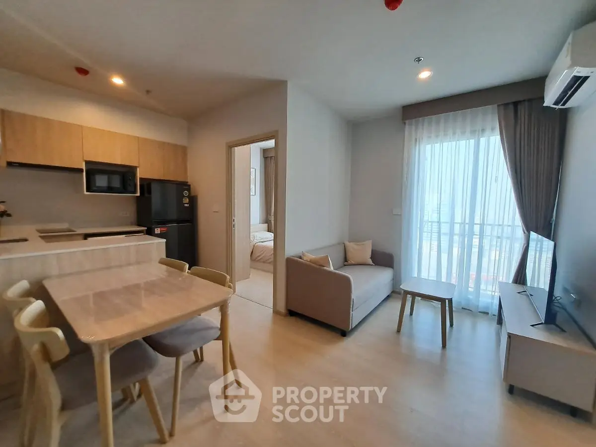 Modern open-plan living room with kitchen and dining area, featuring stylish furniture and natural light.