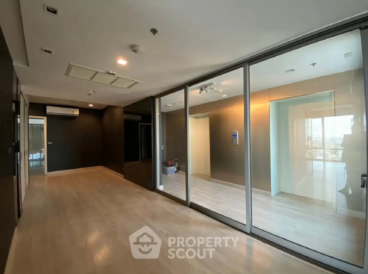 Spacious modern living room with glass partition and wooden flooring