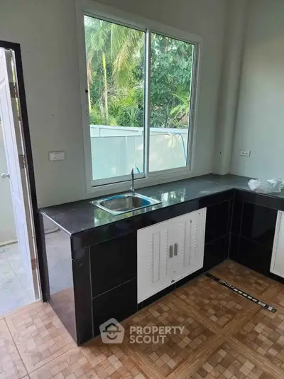 Modern kitchen with sleek black countertops and large window view