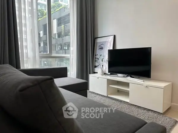 Modern living room with sleek furniture and large window view in urban apartment.