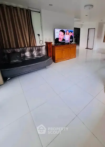 Spacious living room with modern decor and large TV, perfect for relaxation and entertainment.