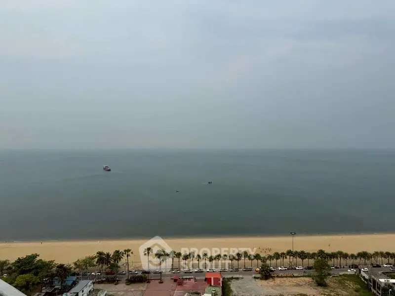Stunning beachfront view from high-rise property overlooking serene ocean and sandy shore.