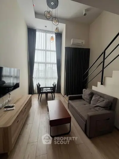 Modern living room with high ceiling, stylish furniture, and large windows for natural light.