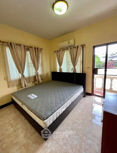 Spacious bedroom with large windows and balcony access in a cozy home.