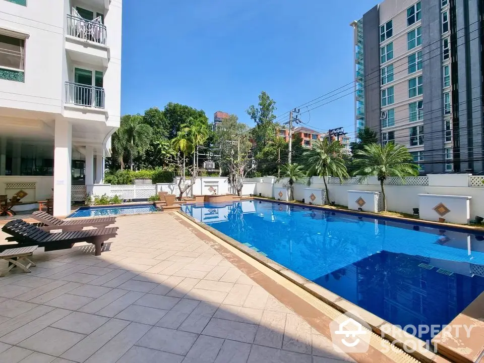 Luxurious apartment complex with stunning outdoor pool and sunbathing area.