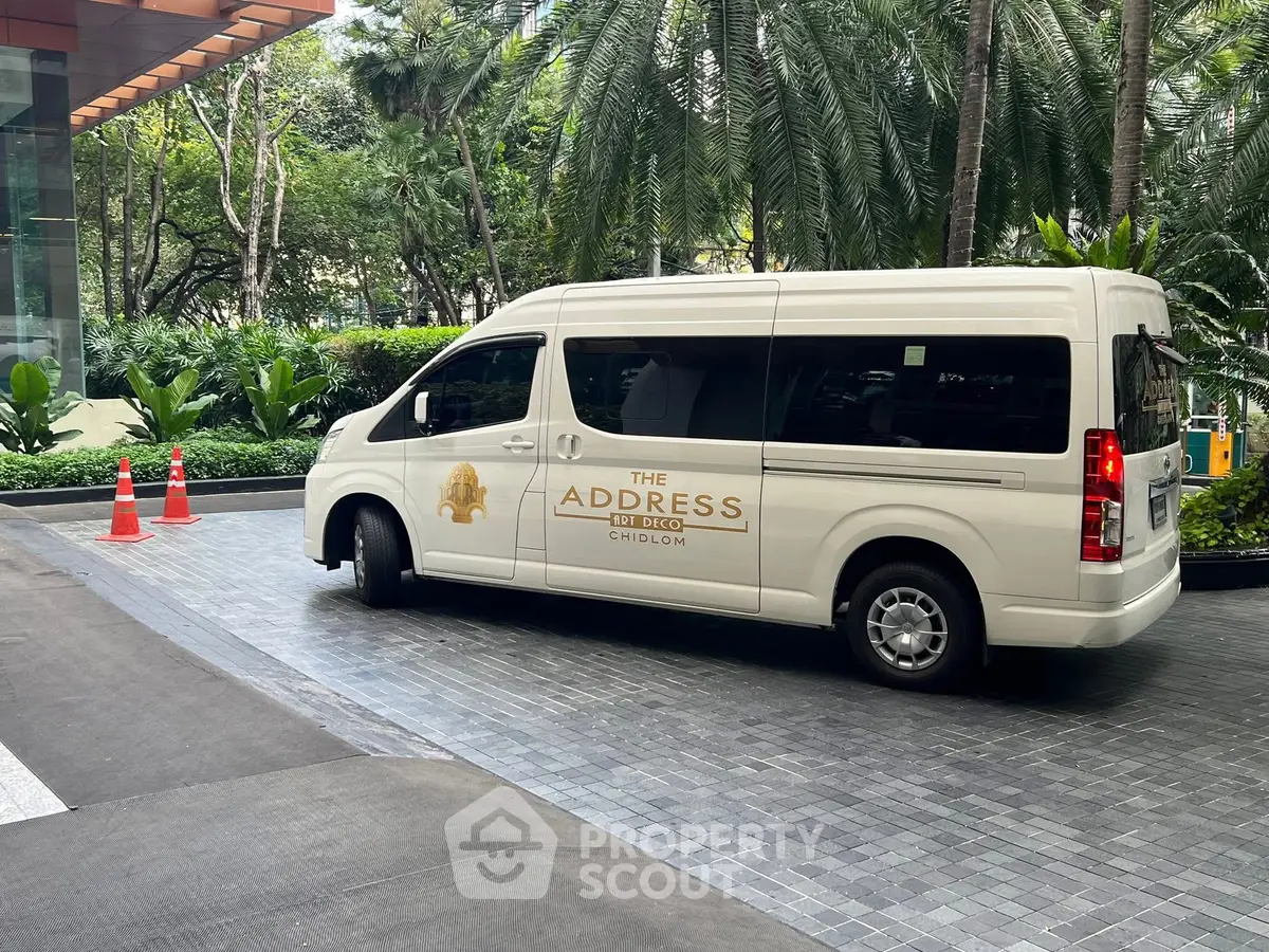 Luxury condominium entrance with branded shuttle van and lush greenery