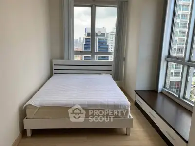 Modern bedroom with city view, featuring a cozy bed and large windows in a high-rise apartment.