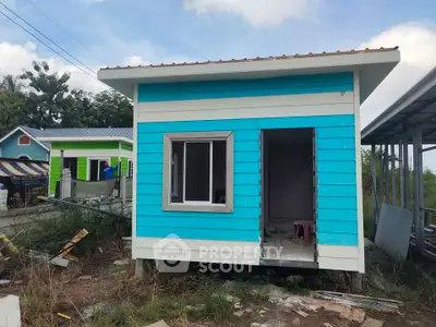 Charming small blue house under construction with vibrant exterior and open doorway.