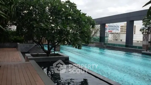 Luxurious rooftop pool with city views and lush greenery in a modern residential complex.