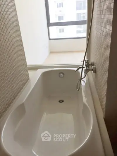 Modern bathroom with sleek bathtub and large window offering natural light.