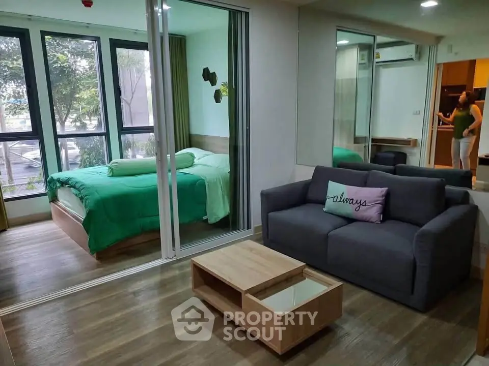 Modern studio apartment with cozy living area and bedroom separated by glass doors, featuring stylish decor.