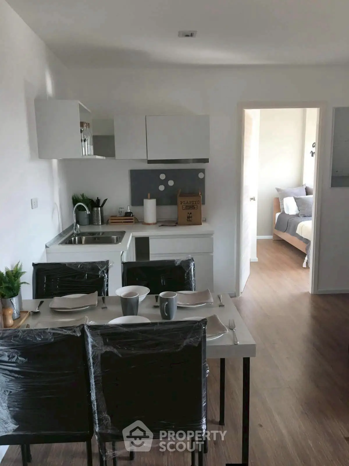 Modern open-plan kitchen and dining area with sleek design and cozy bedroom view.