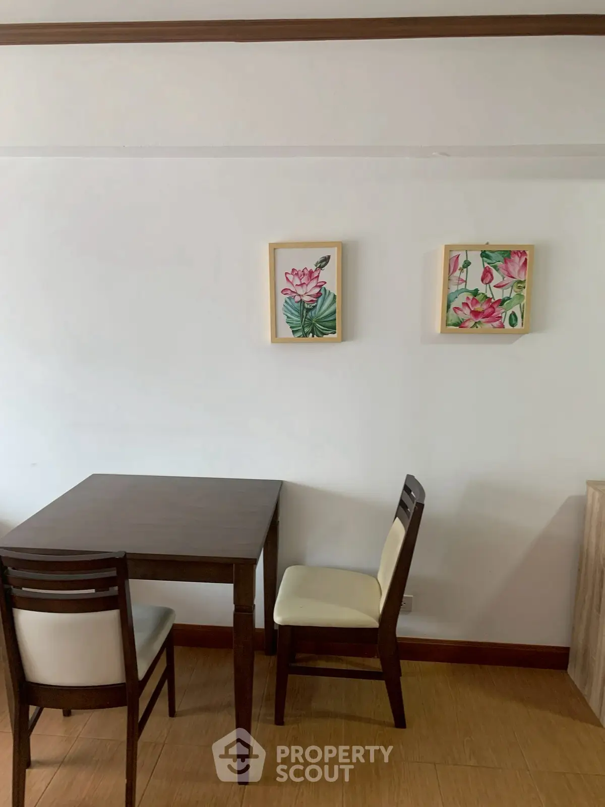 Cozy dining nook with wooden table and chairs, adorned with floral wall art.