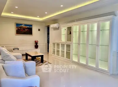 Spacious living room with elegant white furniture and built-in glass cabinets