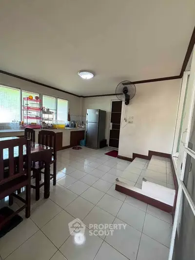 Spacious kitchen with modern appliances and dining area, featuring a sleek refrigerator and ample natural light.