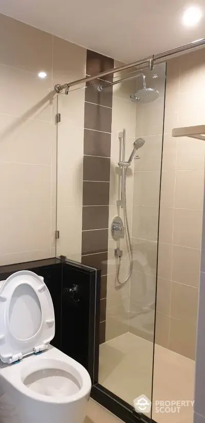 Modern bathroom with glass shower and sleek fixtures in contemporary apartment.