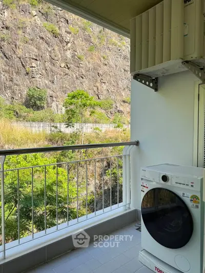 Charming balcony with scenic mountain view and modern washing machine, perfect for relaxation and convenience.