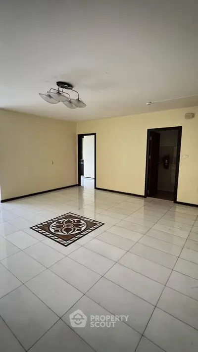 Spacious empty living room with elegant tile flooring and modern ceiling light fixture.