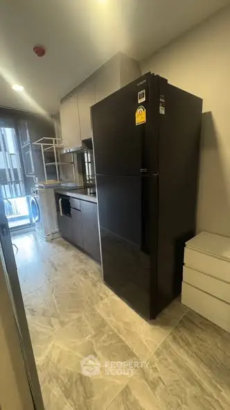 Modern kitchen with sleek black fridge and stylish cabinetry in a contemporary apartment.