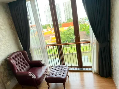 Charming living room with elegant armchair and ottoman, featuring a stunning city view through large windows.