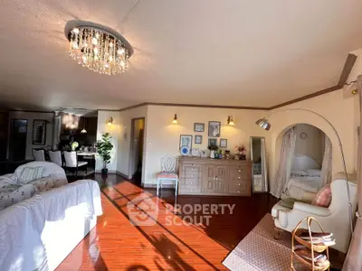 Spacious living room with elegant decor and natural light, featuring a cozy reading nook and stylish chandelier.
