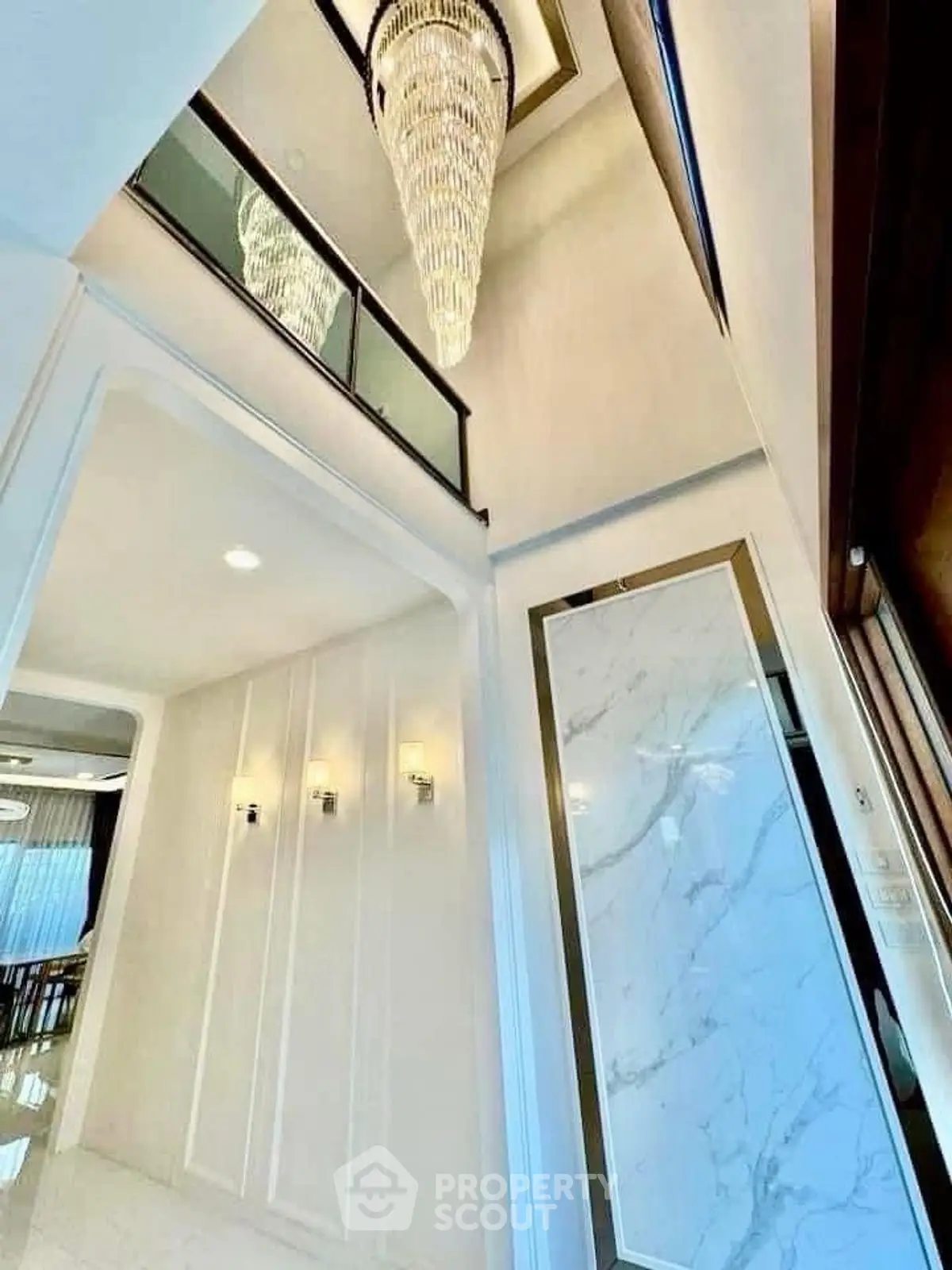 Luxurious high-ceiling entrance with elegant chandelier and marble accents