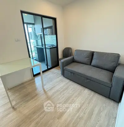 Modern living room with sleek gray sofa and glass table, featuring a balcony view.
