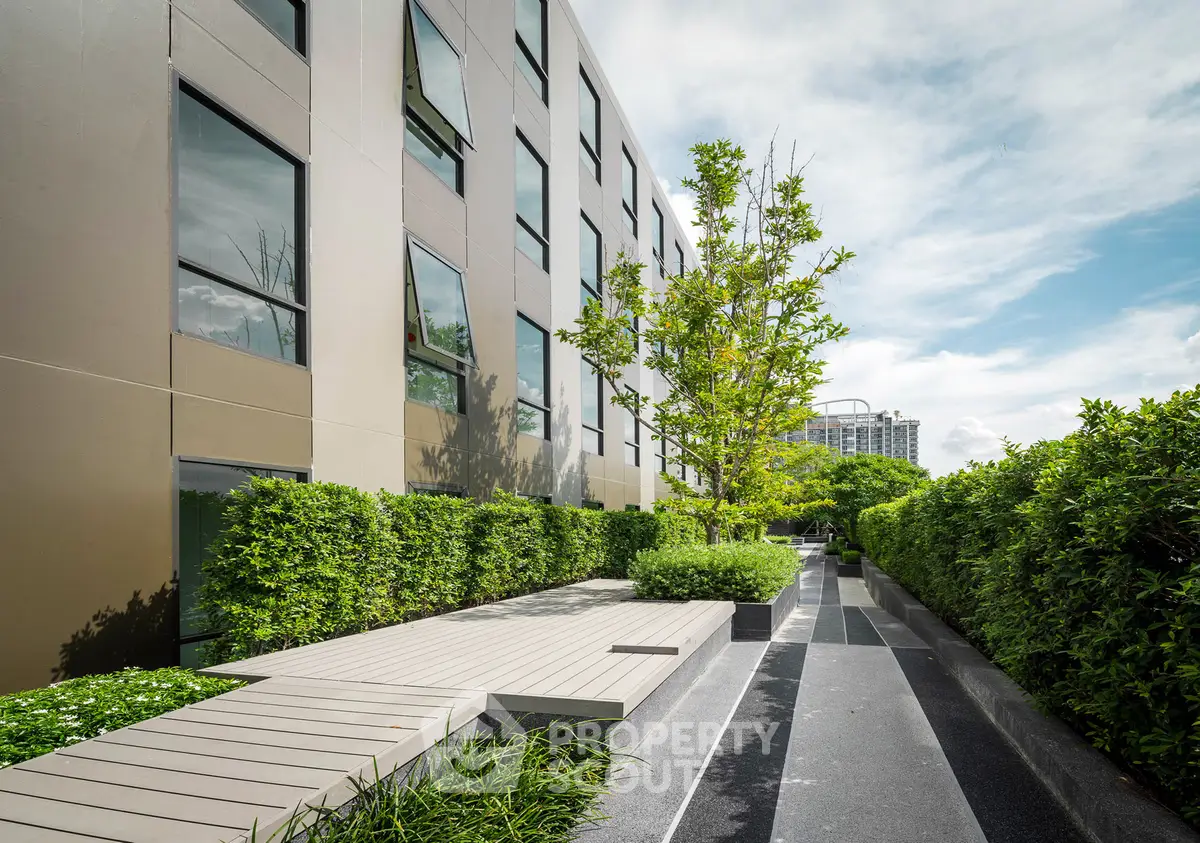 Modern building exterior with lush greenery and sleek walkway design.