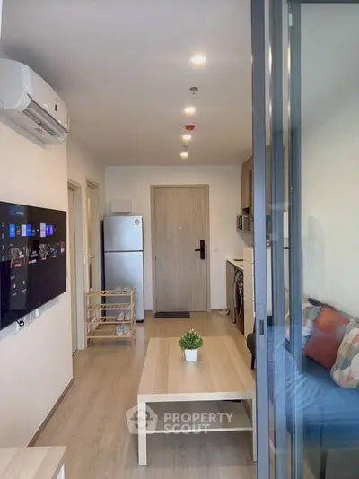 Modern living room with sleek furniture and appliances in a cozy apartment.